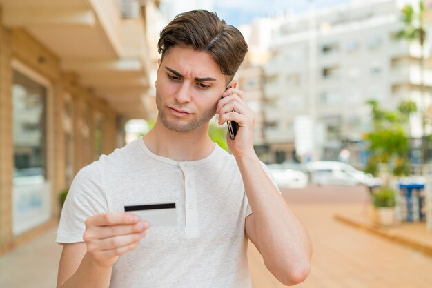 Young handsome man buying with the mobile with a credit card