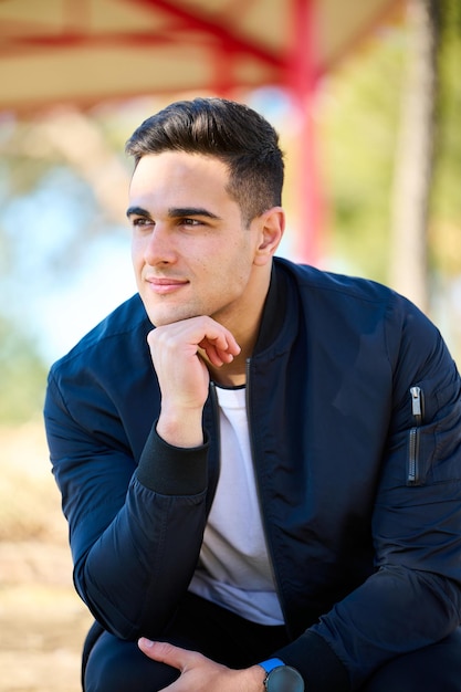 Young handsome man in casual clothes sitting in the city park after playing sports