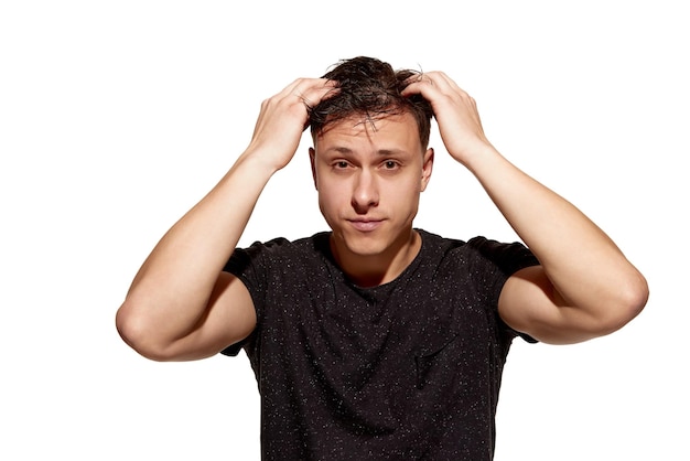 Young handsome man in casual tshirt combs his hair with hands wellbeing concept of mens health body