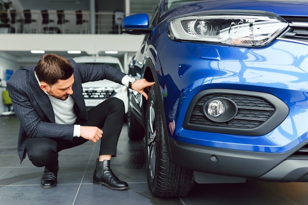 Young handsome man choosing a car in a car showroom