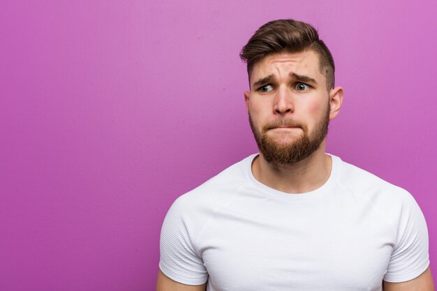 Photo young handsome man confused, feels doubtful and unsure