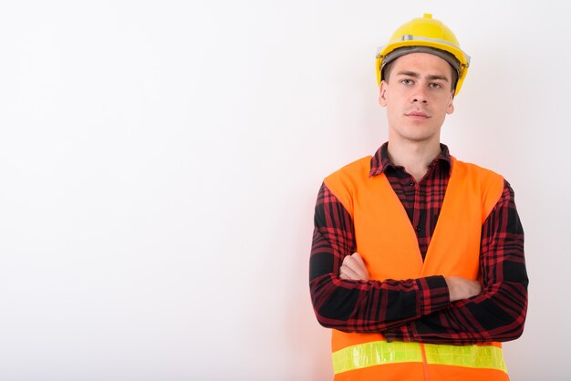 Young handsome man construction worker on white wall