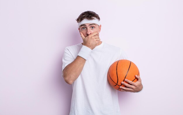 Young handsome man covering mouth with hands with a shocked. basketball concept