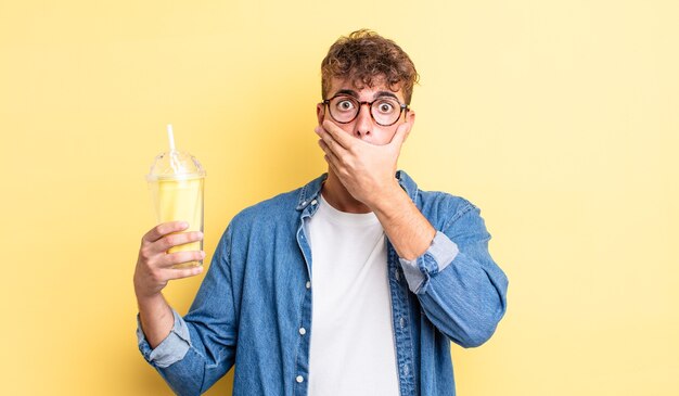 Young handsome man covering mouth with hands with a shocked. milkshake concept