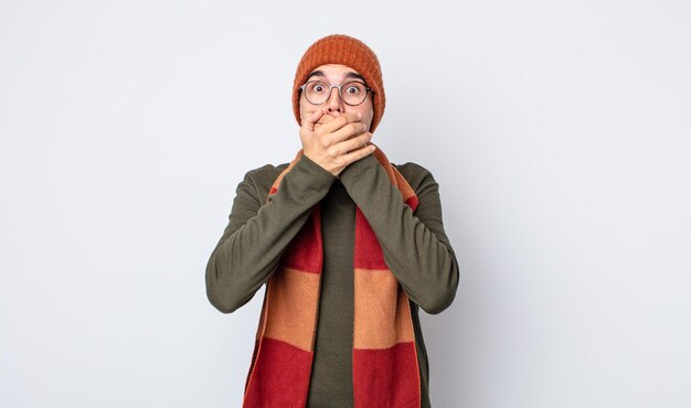 young handsome man covering mouth with hands with a shocked. winter clothes concept
