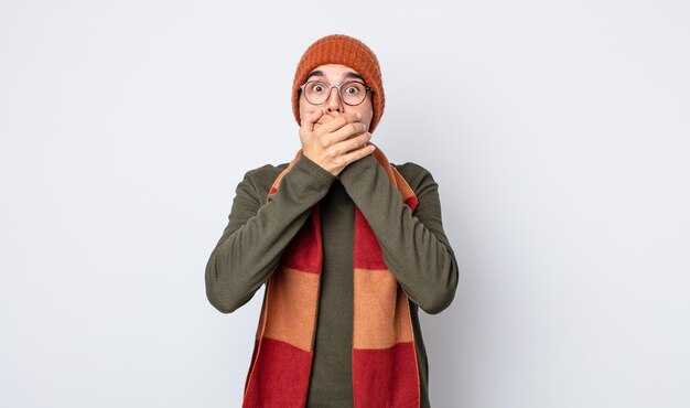 Young handsome man covering mouth with hands with a shocked. winter clothes concept