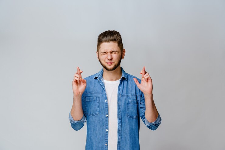 Photo young handsome man crosses fingers and makes a wish