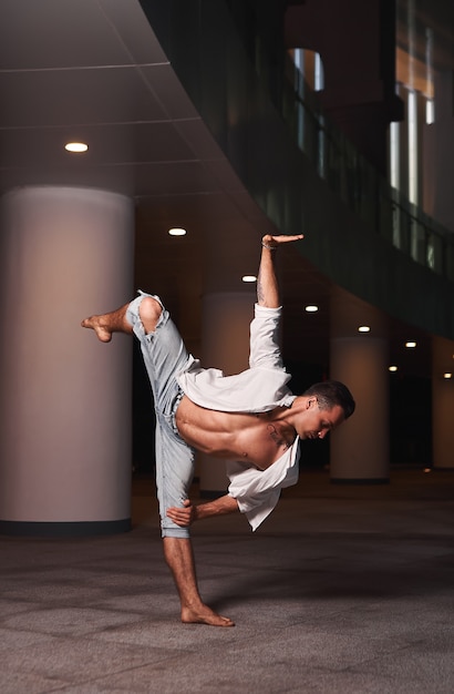 young handsome man dancing ballet in the outdoorthe dancer is wearing a white shirt and jeans