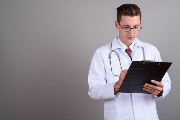 young handsome man doctor wearing eyeglasses on gray