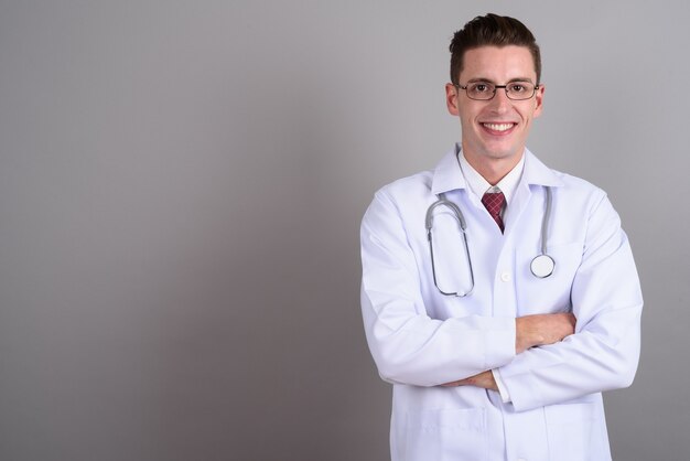 young handsome man doctor wearing eyeglasses on gray