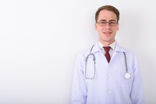 Young handsome man doctor wearing eyeglasses on white wall