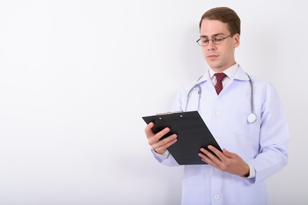 Young handsome man doctor wearing eyeglasses on white wall