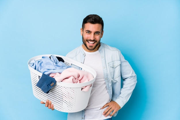 Young handsome man doing laundry isolated laughing and having fun.