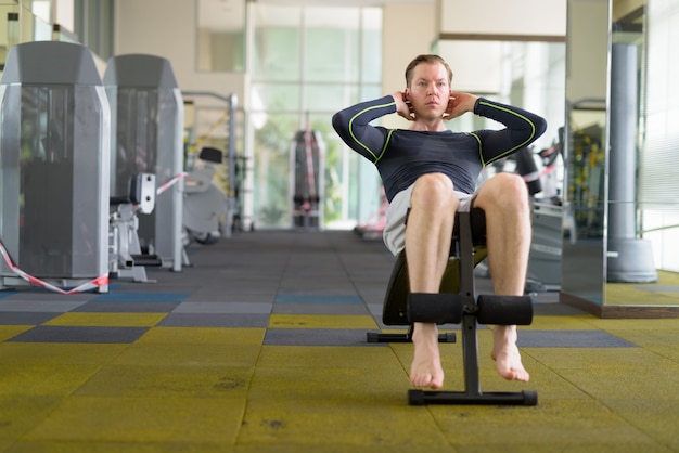 young handsome man doing sit ups at the gym during covid-19