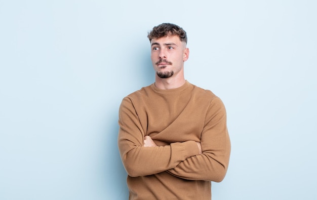 Photo young handsome man doubting or thinking, biting lip and feeling insecure and nervous, looking to copy space on the side