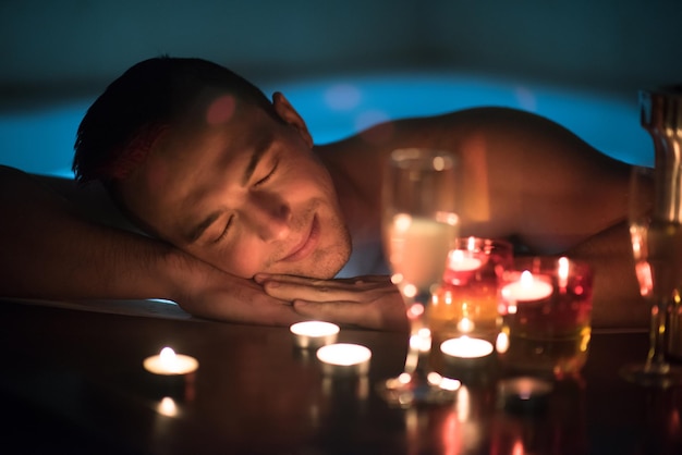 young handsome man enjoys relaxing in the jacuzzi with candles and champagne at luxury resort spa