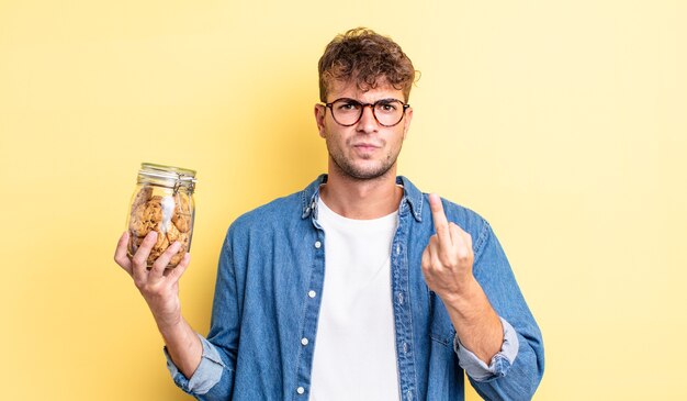 Young handsome man feeling angry, annoyed, rebellious and aggressive. cookies bottle concept