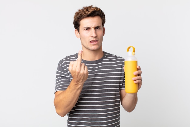 Young handsome man feeling angry, annoyed, rebellious and aggressive and holding a coffee thermos