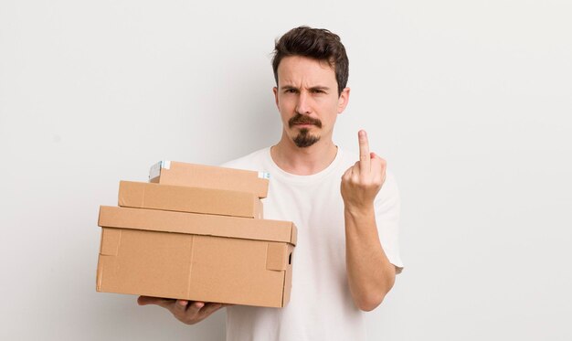 Young handsome man feeling angry annoyed rebellious and aggressive shipping boxes concept