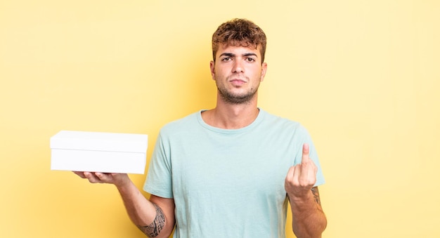 Young handsome man feeling angry, annoyed, rebellious and aggressive. white box concept