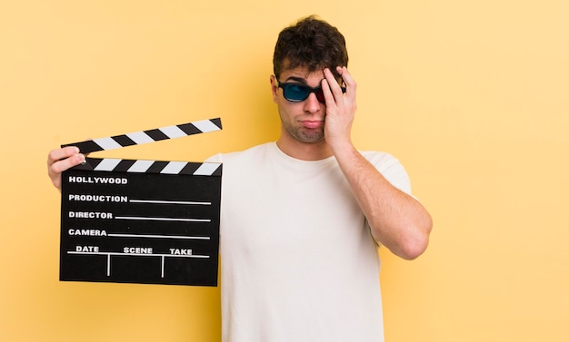 Young handsome man feeling bored frustrated and sleepy after a tiresome cinema clapper concept