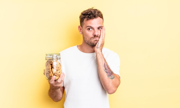 Young handsome man feeling bored, frustrated and sleepy after a tiresome cookies bottle concept