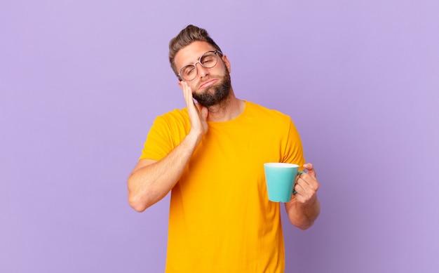 Young handsome man feeling bored, frustrated and sleepy after a tiresome. and holding a coffee mug