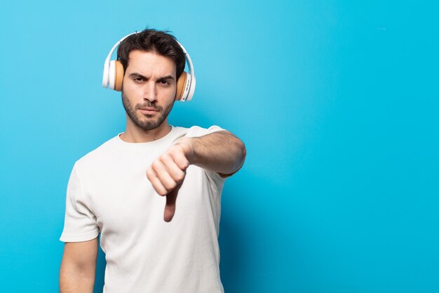 Young handsome man feeling cross, angry, annoyed, disappointed or displeased, showing thumbs down with a serious look