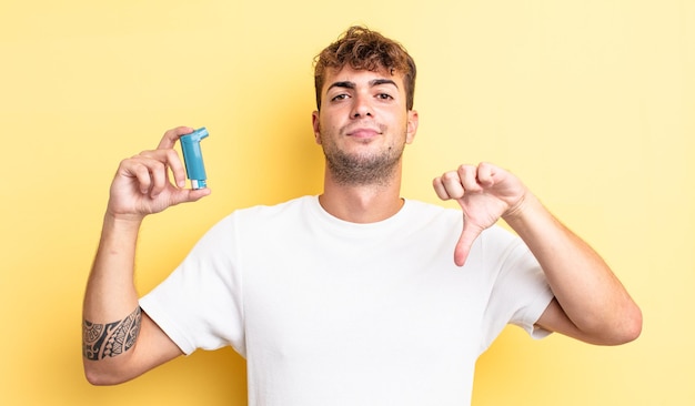 Young handsome man feeling cross,showing thumbs down. asthma concept