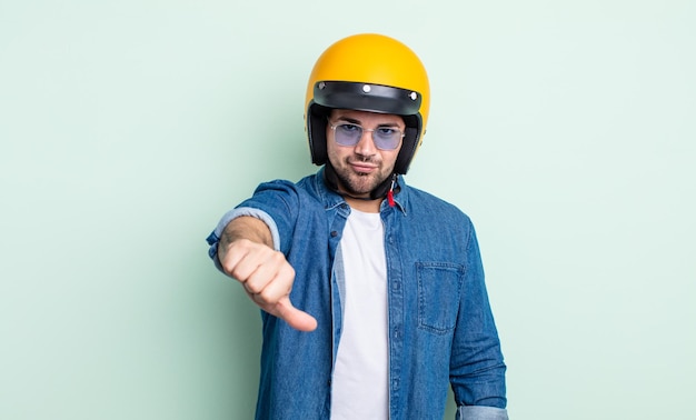 Giovane bell'uomo che si sente arrabbiato, mostra i pollici in giù. concetto di casco da moto