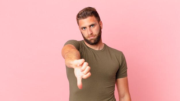 Photo young handsome man feeling cross,showing thumbs down