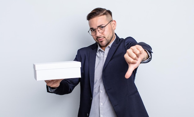 Young handsome man feeling crossshowing thumbs down white box concept