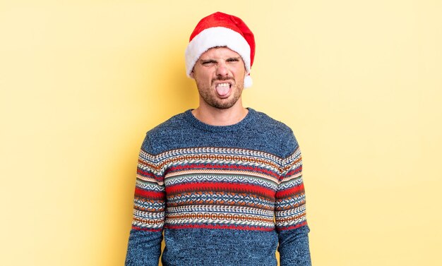 young handsome man feeling disgusted and irritated and tongue out. christmas concept