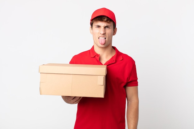 Young handsome man feeling disgusted and irritated and tongue out delivery package service concept.