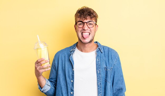 Young handsome man feeling disgusted and irritated and tongue out. milkshake concept