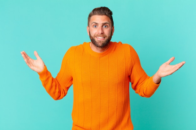 Young handsome man feeling happy and astonished at something unbelievable