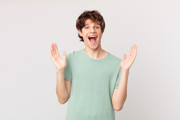 Young handsome man feeling happy and astonished at something unbelievable