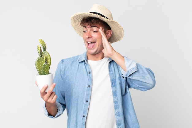 Young handsome man feeling happy, excited and surprised. farmer holding a decorative cactus