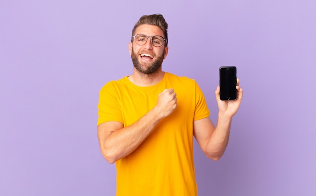 young handsome man feeling happy and facing a challenge or celebrating. cell concept