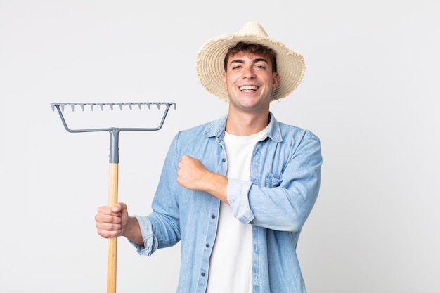 Young handsome man feeling happy and facing a challenge or celebrating. farmer concept