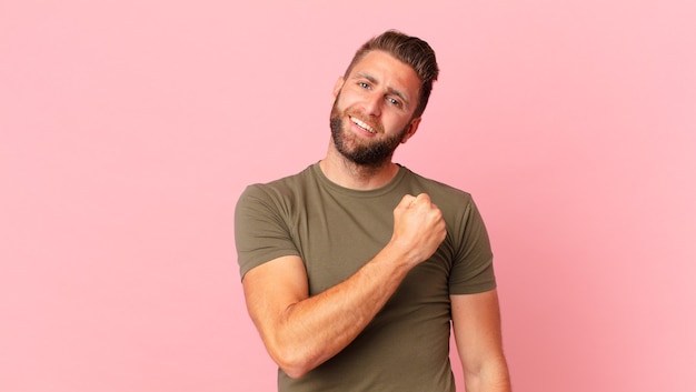 Young handsome man feeling happy and facing a challenge or celebrating