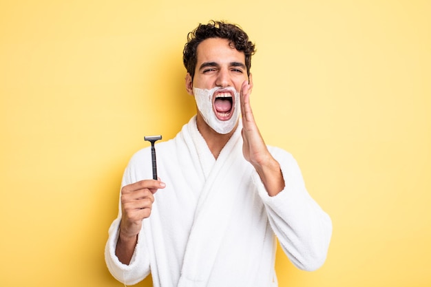 Young handsome man feeling happy,giving a big shout out with hands next to mouth. shaving and foam concept