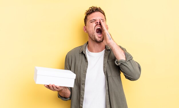 Young handsome man feeling happy,giving a big shout out with hands next to mouth. white box concept