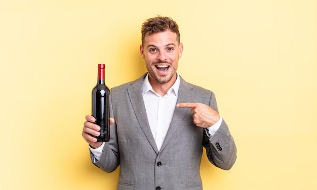 Young handsome man feeling happy and pointing to self with an excited. bottle of wine concept