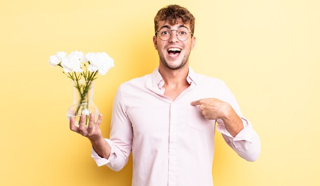 Young handsome man feeling happy and pointing to self with an excited. flowers concept