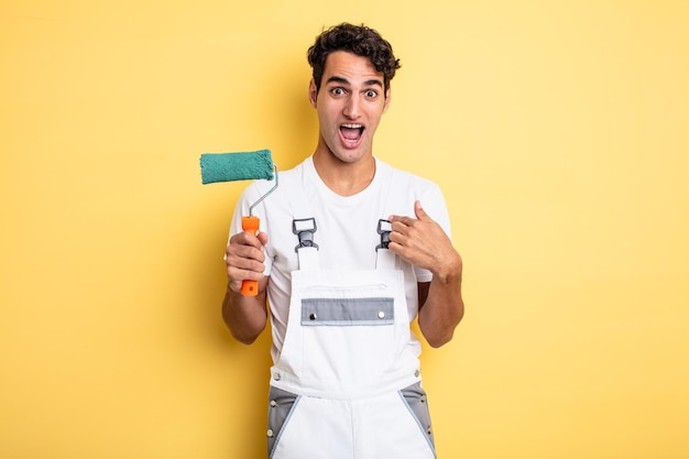 Young handsome man feeling happy and pointing to self with an excited painting home concept