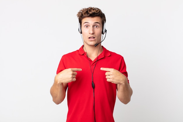 Young handsome man feeling happy and pointing to self with an excited. telemarketer concept