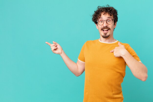 Young handsome man feeling happy and pointing to self with an excited