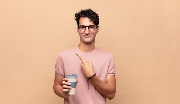 Young handsome man feeling happy and pointing to the side and upwards, showing object