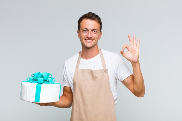 Young handsome man feeling happy, relaxed and satisfied, showing approval with okay gesture, smiling